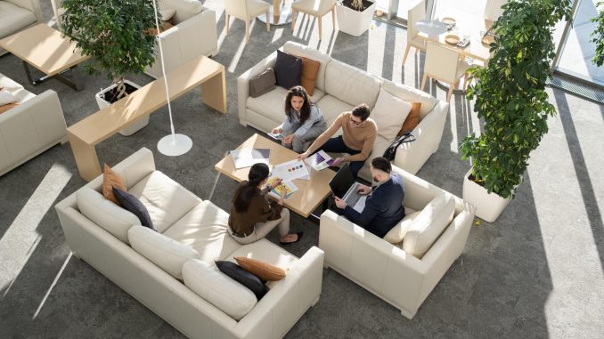 Group of young auditors of high tech corporation discussing documents with data and analyzing it while gathered around table in office